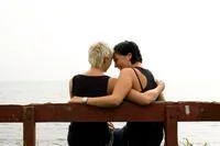 Two women sitting on a bench hugging