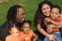 Bi-racial family smiling sitting on grass