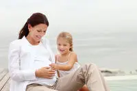 mother and young daughter sitting on beach