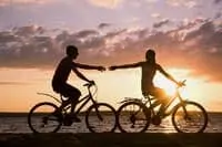 couple riding bikes and holding hands