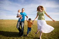 family of 4 holding hands in a field