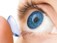 A bright blue eye with a finger putting on a contact lens.