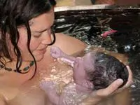 mother holding newborn in a therapy pool