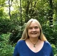 Ann Coco standing in front of a forest