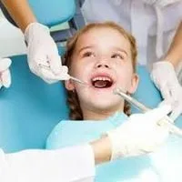 young blond girl looking up at dentist with mouth open for exam, dental sealants Melrose, MA dentist