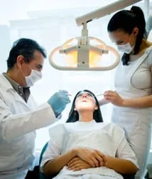 woman in dental chair having mouth examined by dentist and assistant, general dentist in Great Neck, NY