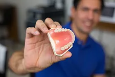 man holding up denture mold with teeth, dentures in Arlington, VA