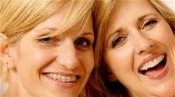 two woman smiling, one with braces