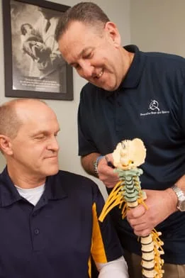 Dr. Bubanic pointing to model spine with patient