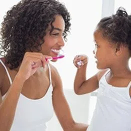 Mother showing a small child how to brush teeth
