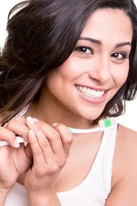 beautiful dark haired woman smiling holding toothbrush, nice white teeth, cosmetic dentistry Livonia, MI
