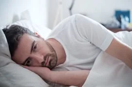 Man laying in bed depressed