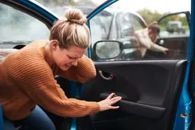 woman holding neck while getting out of car