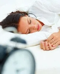 woman sleeping with alarm clock, sleep apnea appliance in Concord, NC