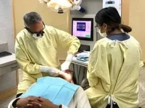 Dr. James Warren and female dental assistant working on patient in chair getting dental veneers Millbrae, CA