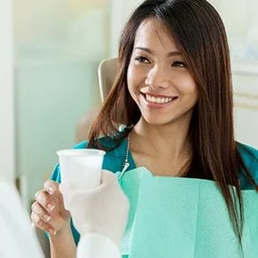 A dental patient smiling and taking a cup of water - Dentist San Diego CA