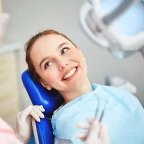A woman in dental chair smiling and looking at the dentist