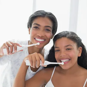 Young girls brushing their teeth and smiling