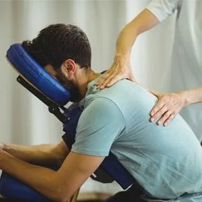 Chiropractic patient receiving a back treatment as his face rests in a face cradle