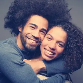 A family with two young children smiling together