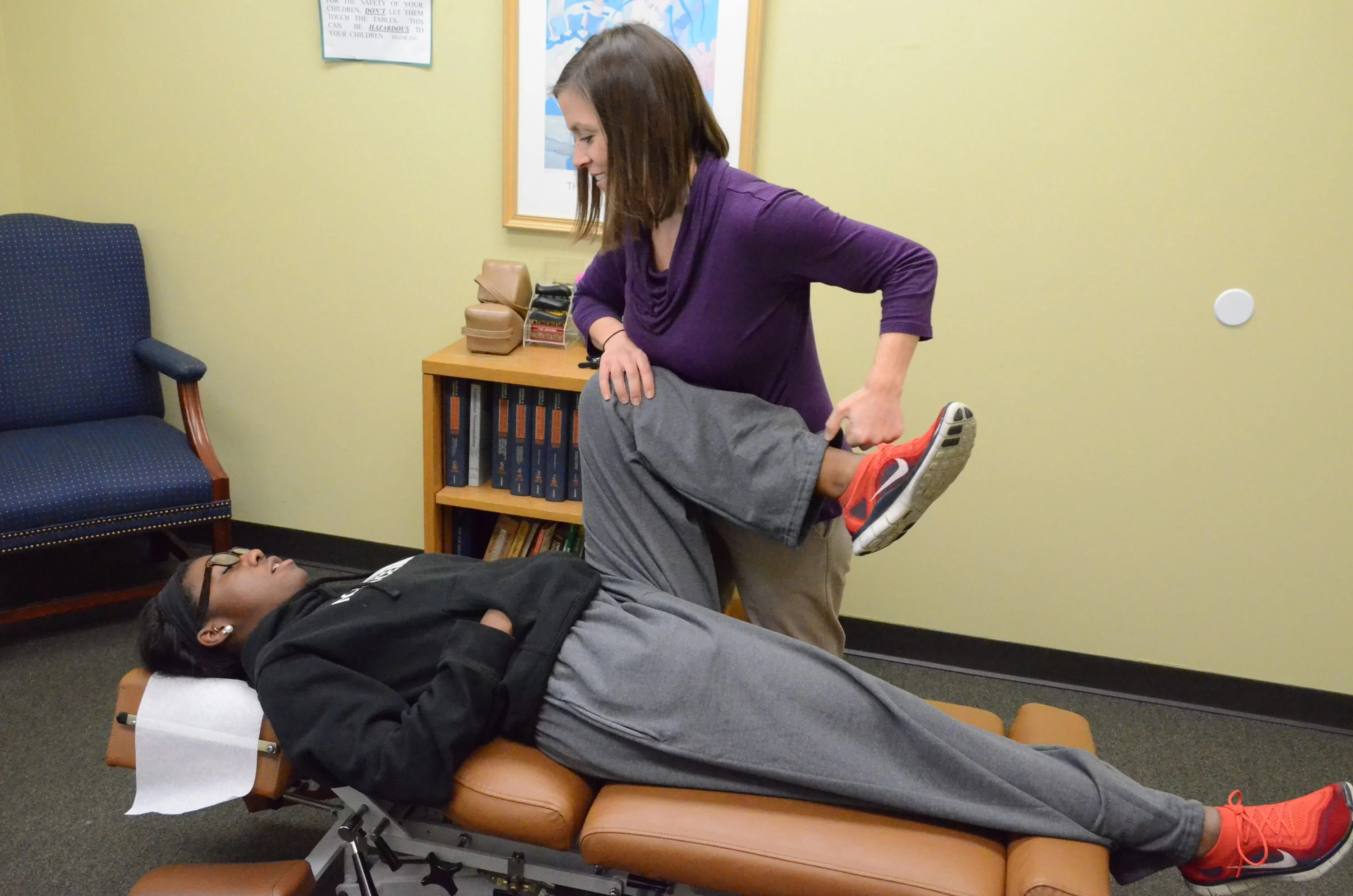 chiropractor adjusting patient's knee on table