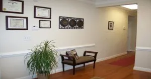 hallways in west cobb office. Cushioned bench in center next to a leafy plant. hardwood floors