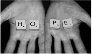 two hands holding scrabble pieces that say hope