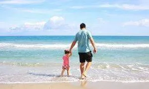 father walking on beach with child