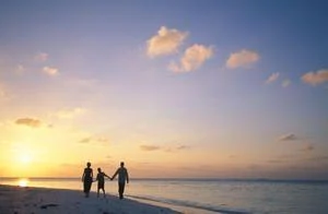 Happy family walking on the beach at sunset