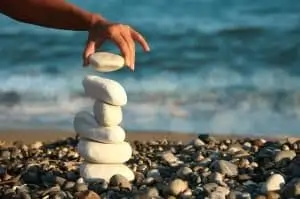 Hand stacking white rocks on a beach