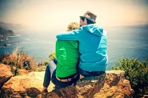 lovely couple sitting on cliff looking at the sea