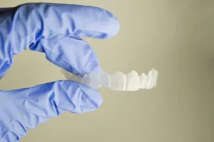 blue gloved hand holding clear teeth aligner, Invisalign clear braces Millbrae, CA dentist