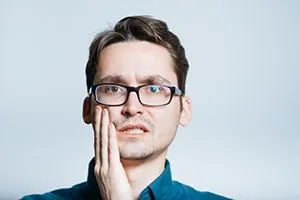 handsome man has a toothache isolated on a gray background