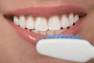 close up of woman's mouth showing teeth with veneers, toothbrush head near mouth, dentist Huntsville, AL cosmetic dentistry