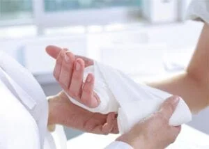 person getting their hand wrapped by a medical professional