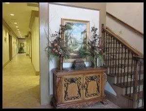 Interior of BridgeMill office. Stairway on right, hallway on left. Flower arrangement on top of cabinet in center.
