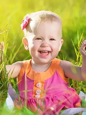baby girl in pink dress sitting in grass, pediatric dentistry Colonial Heights, VA dentist