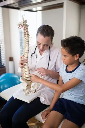 young boy and his chiropractor looking at a model of the human spine 