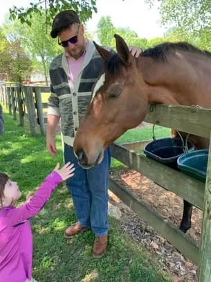 girl petting brown horse nose