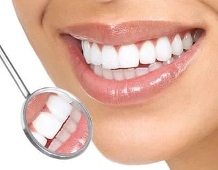 close up of dental mirror next to woman's smiling mouth, bright white teeth, cosmetic dentistry College Point, NY dentist