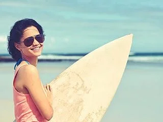 woman wearing sunglasses carrying a surfboard