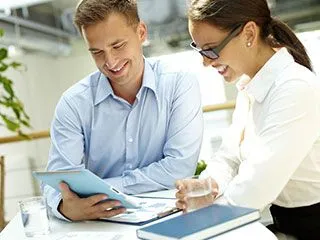 man and woman smiling looking down at files on table, female dentist North York, ON