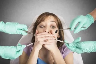 girl with hands over mouth surrounded by hands holding dental tools, afraid of dentist Tarzana, CA sedation dentistry
