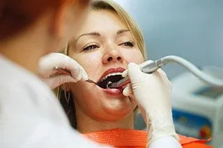 dentist using tools to perform root canal in blond woman's mouth, root canal Farmingdale, NY dentist