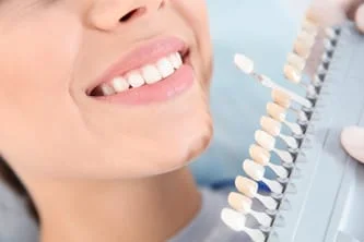 woman smiling as dentist is holding crowns by her mouth to match tooth color. cosmetic dentistry Hayward, CA dentist