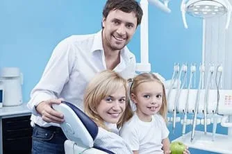husband standing next to dental chair with wife and child, Katy, TX Family Dentist