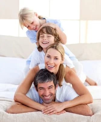 young family piled on top of each other posing and smiling, Beeville, TX family dentistry