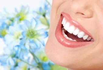 close up of woman's mouth smiling straight white teeth, flowers in background, Cosmetic Dentistry Narberth, PA