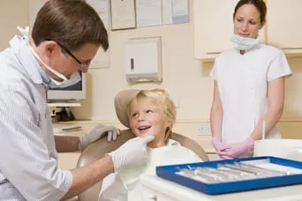 young boy sitting in dental chair talking to male dentist, pediatric dentistry Encinitas, CA dentist