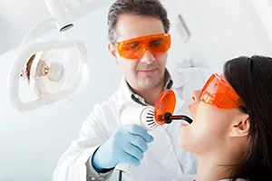 male dentist using dental laser in woman's mouth for Laser Gum Disease Treatment Plantation, FL